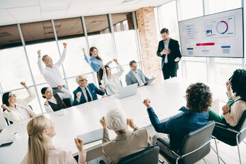 Team of business professionals collaborating in a modern meeting room celebrating success and...