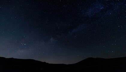 Fototapeta premium Vast, star-filled night sky over dark, rolling hills