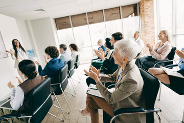 Professional team applauding during an engaging group training session at an office setting led by...