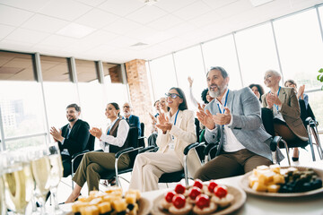 Business team applauding during a corporate meeting in a modern office setting with diverse...