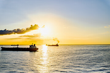 Obraz premium Cargo ships sailing at sunset, towards the port of Barcelona 