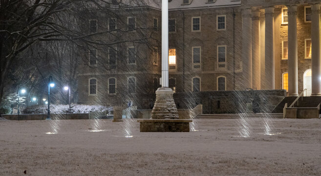 Illuminated view of the historic Old Main clock tower at Pennsylvania State University against a dark winter night sky