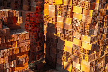 Stacks of red clay bricks in sunlit construction zone