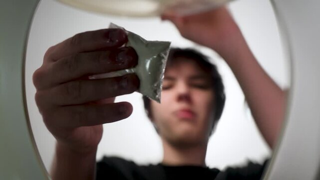 Point of view shot from inside a toilet showing a teenager discarding a small plastic bag with white powder. Concept of drug disposal, prevention, addiction, and illegal substances. Stop narcotics