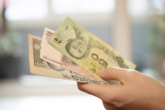 Woman s hand holding variety of international currency banknotes. Concept of travel budget, foreign exchange, or global finance for business.