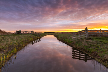 A peaceful awakening in the Kruiszwin nature reserve beneath a colorful, cloud-filled sky. Nature...