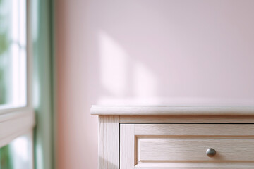 Fototapeta premium Light wood dresser drawer with soft window light casting shadows on a pink wall