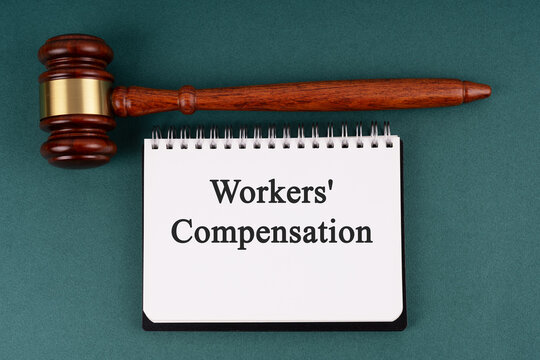 Gavel and notepad with text workers compensation on green background