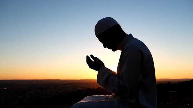 A man praying in solitude at sunset on a hill, captured in a serene video landscape