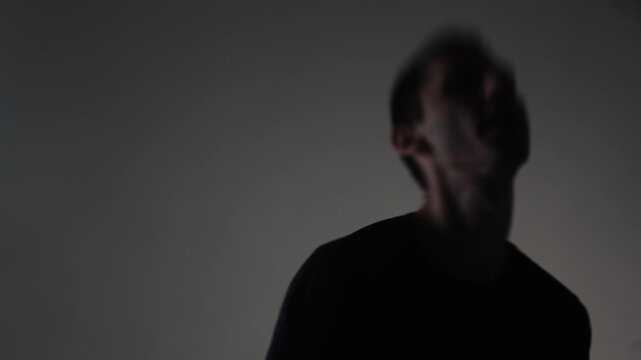 A raw, dynamic shot of a young rock vocalist screaming with destructive emotion. Motion blur visualizes his unstable psychological state and aggressive delivery.