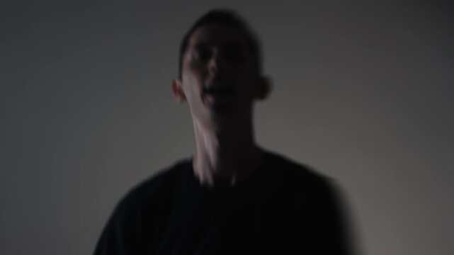 A young man in a frenzied state screams aggressively into the frame as a rock singer. Motion smear conveys his unstable, emotionally charged performance.