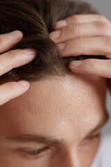 Close-up of a person's hands gently touching their dark brown hair and forehead