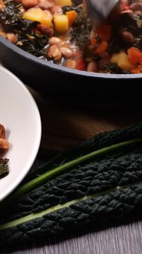Video verticale, zuppa versata con il mestolo dalla pentola di cottura, servita nel piatto