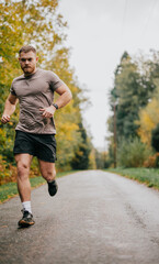 Fototapeta premium A man is running on a road with trees in the background