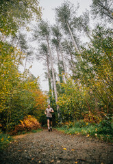 Fototapeta premium A man is running through a forest with trees in the background