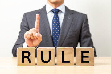 「RULE」と書かれたブロックとビジネスマン