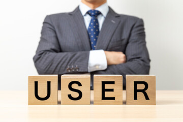 Obraz premium 「USER」と書かれたブロックと腕組みをするビジネスマン