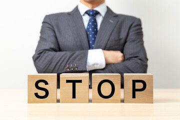 Obraz premium 「STOP 」と書かれたブロックと腕組みをするビジネスマン