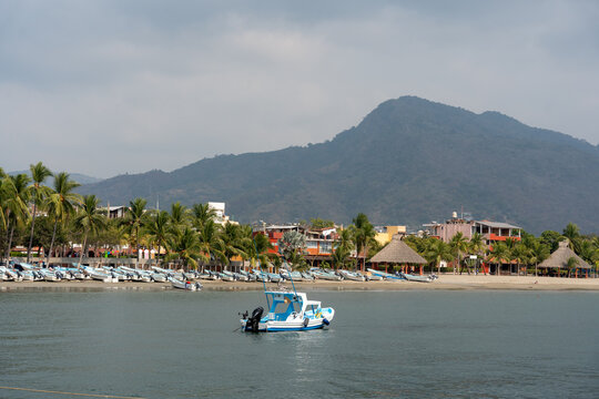 View of the beach in the bay of Ixtapa Zihuatanejo with boats in the sea and palm trees on the sand. Tropical landscape of costa grande, Guerrero. Mexico, January 19, 2026.