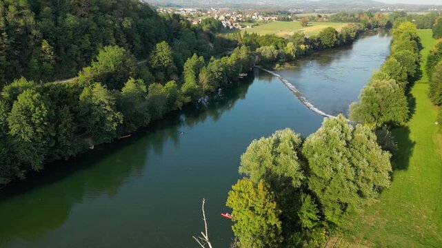 Aerial view of the Kolpa River near Metlika, Slovenia, featuring a small river dam with flowing water, calm green river pools, surrounding forest, and a peaceful rural landscape in summer.