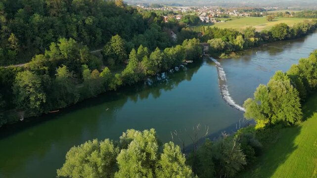 Aerial view of the Kolpa River near Metlika, Slovenia, featuring a small river dam with flowing water, calm green river pools, surrounding forest, and a peaceful rural landscape in summer.