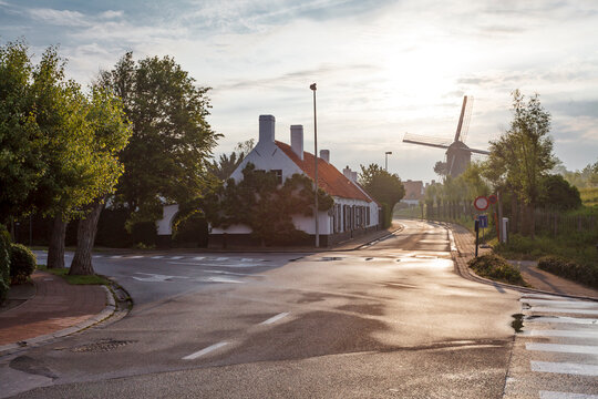 Street with white houses and windmill during the sunset in Knokke, West Vlaanderen, Belgium, Europe