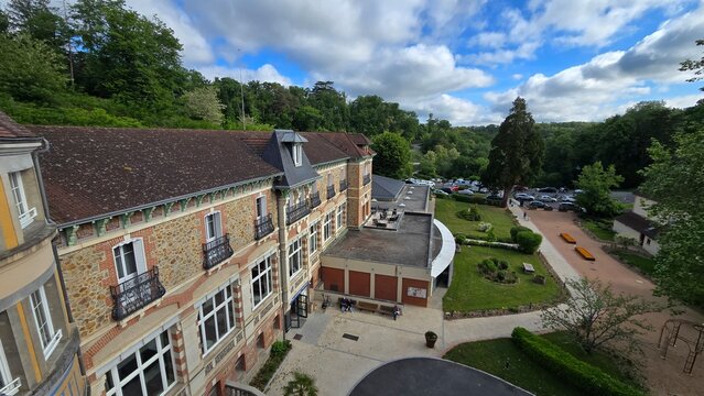 Evaux-les-Bains, Nouvelle-Aquitaine, France - May 29, 2025. Top window view of the Le Grand Hotel, The Originals Relais, and the green courtyard.
