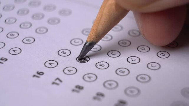 Close-up of a person shading multiple choice circles on an answer sheet during an examination or test