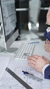 Architects and engineers discussing building blueprint plans on a computer monitor and paper drawings. Business people and architecture concept