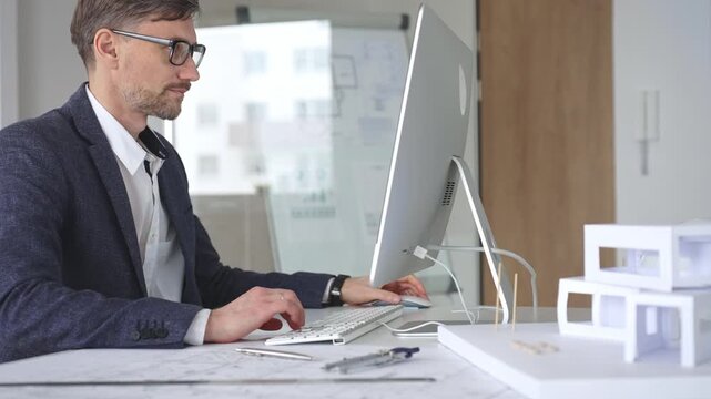 Architect working on computer creating building design, drafting construction plans, modeling house layout. Business and architecture concept