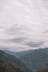 Fototapeta premium Autumn mountains stretch across dramatic valley under clouds