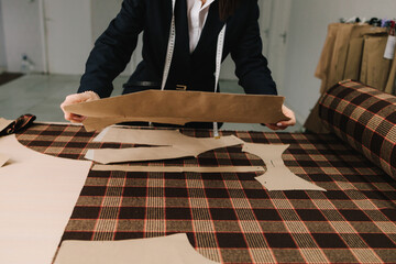 Designer aligns sewing patterns on fabric, preparing layouts for accurate tailoring.