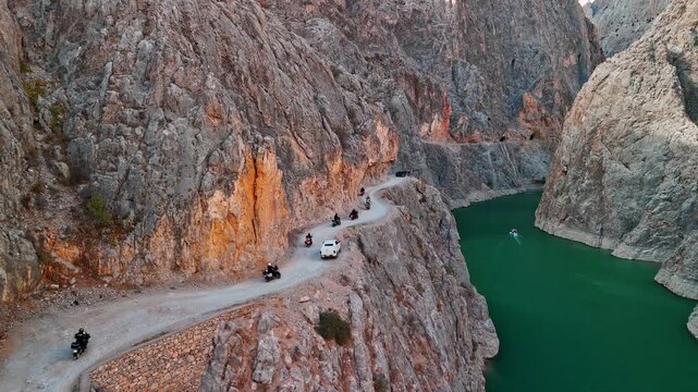 Motorcycle convoy riding on Taşyol road along the Euphrates River in Erzincan, Turkey. Rocky valleys and scenic river landscape captured from aerial perspective.