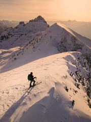 Lone Hiker on Snowy Mountain Ridge at Golden Hour