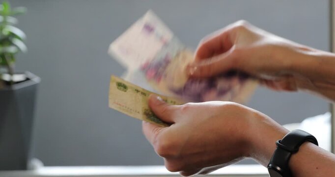 Woman holding chinese yuan renminbi banknotes and counting money. Financial concept of economy, foreign exchange, and income.