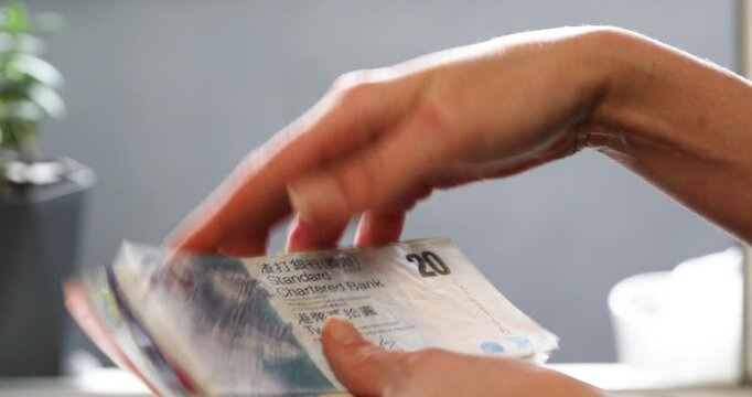 Woman counting money, hong kong dollar banknotes in motion, finance and budget planning concept for wealth management.