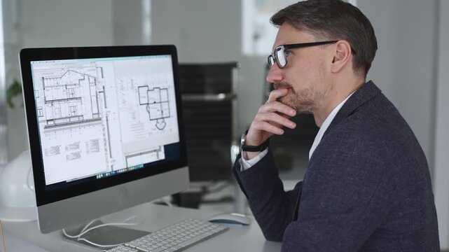 Architect working on building blueprint plans, creating design and engineering structure on desktop computer in office. Business and architecture concept