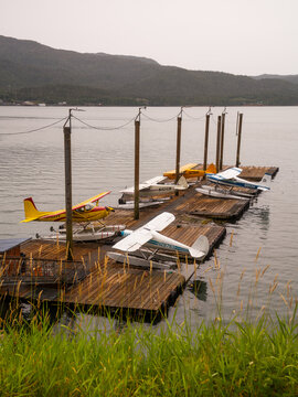 View of floatplanes resting on weathered docks under a muted sky, reflecting in the calm water, a serene scene of Alaskan aviation, Ketchikan, Alaska, United States.