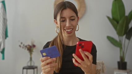Woman checking payment details on creditcard while holding smartphone in building with focused...