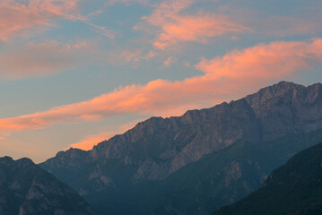 Obraz premium A dramatic mountain landscape at sunset, with a vibrant sky painted in hues of orange and blue