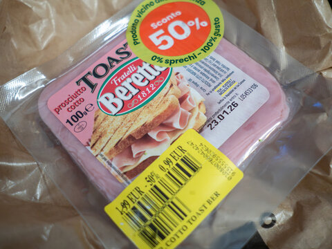 A package of sliced cooked ham with a yellow sticker indicating a 50% discount due to its approaching expiration date