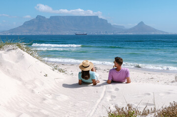 Enjoy a relaxing day at Bloubergstrand beach with stunning views of Table Mountain. A couple sits...