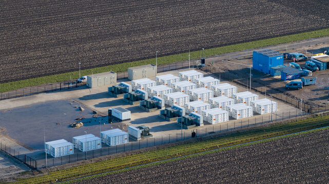 Dronter, Netherlands - 14 January 2026: Aerial view of a neatly arranged energy storage facility, contrasting starkly with the surrounding dark, ploughed fields.
