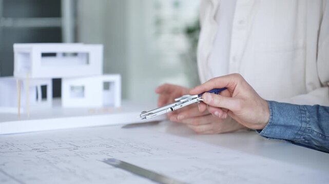 Architects collaborating on blueprint plans, discussing engineering details and project designs, planning construction development with a laptop in a modern office environment