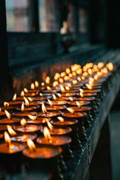 View of flickering candlelight reflecting warm glows on metallic surfaces, creating a serene atmosphere in Jambay Lhakhang, Jakar, Bumthang, Bhutan.