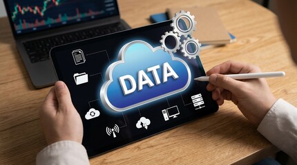 Person using stylus on tablet displaying cloud data icon and interconnected digital symbols with gears above and laptop with financial graph in background technology network information