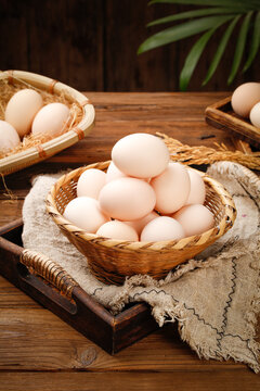 Fresh Farm Eggs with White Shells in Wicker Baskets on Rustic Wood Background