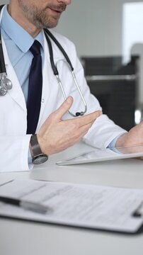 Doctor discussing medical information and treatment plans with a patient during a healthcare consultation in a clinic office. Medicine, healthcare and science concept