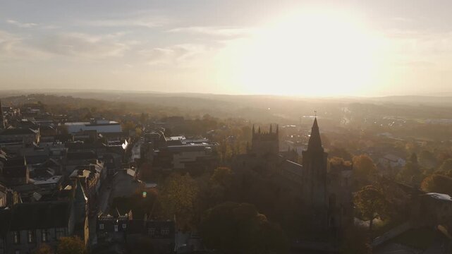 Aerial view of Dunfermline Abbey and the palace ruins, bathed in the warm glow of the setting sun, contrasting with the surrounding lush greenery, Dunfermline, Scotland, United Kingdom.