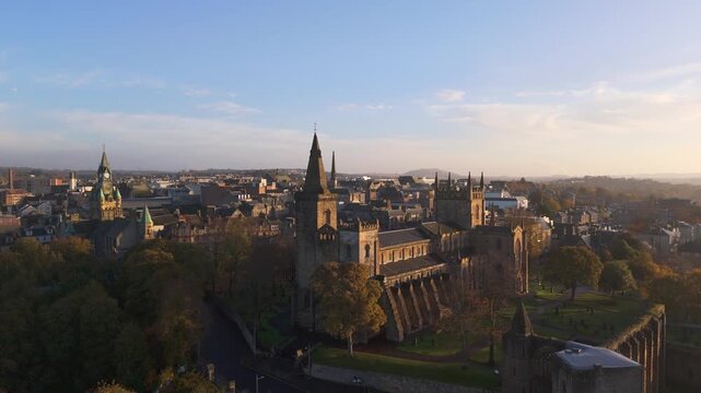 Aerial view of Dunfermline Abbey Church, its gothic spires piercing the skyline amidst a landscape bathed in the warm hues of dawn, Dunfermline, United Kingdom.